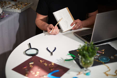 Designer with a pencil sketch seated at the laptop