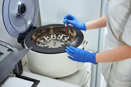 Scientist with a vacutainer standing before the laboratory deviceの写真素材