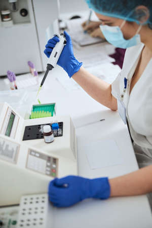 Biochemist using a pipettor for conducting a hematological testの写真素材