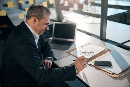 Intelligent man working on project in modern officeの写真素材