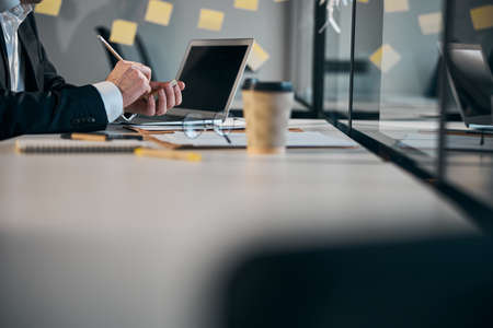 Male worker hands writing on sticky notes in officeの写真素材