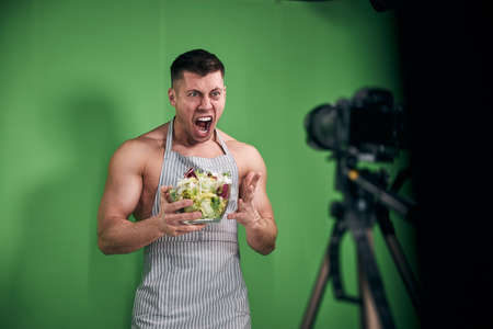 Athletic young man recording video and screaming in studioの写真素材