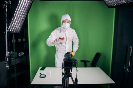 Male doctor in protective mask and suit recording video for blogの写真素材