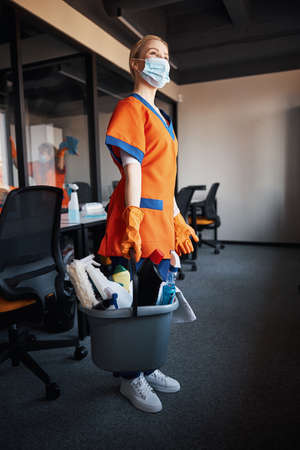 Janitor with cleaning products in her hands looking into the distanceの写真素材