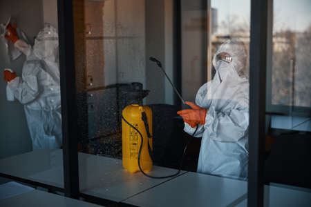 Cleaners in protective gear doing the antiviral disinfectionの写真素材