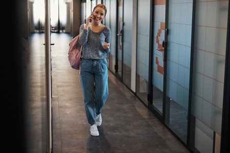 Smiling office employee talking on the phone in the hallwayの写真素材