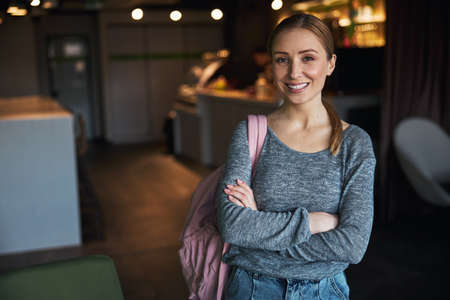 Front view of a smiling female employee with her arms crossed looking in front of her