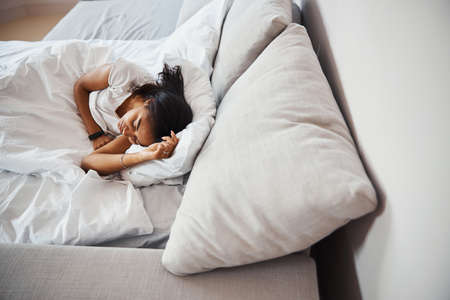 Beautiful young woman sleeping in bed at homeの写真素材