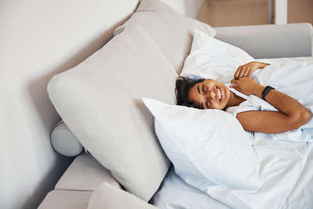 Cheerful young woman lying in bed at home