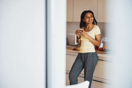 Cheerful young woman drinking tea at home