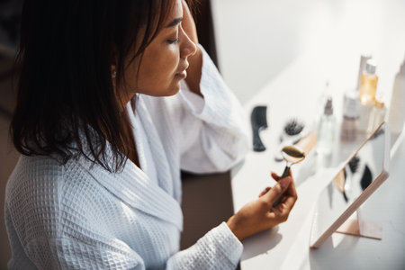 Beautiful young woman using face massager at homeの写真素材