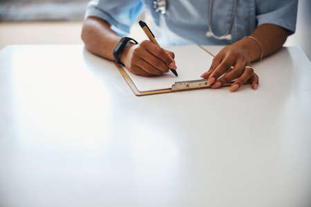 Female doctor writing on clipboard in clinicの写真素材