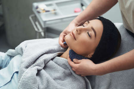 Female patient receiving a neck massage from a professional cosmetician