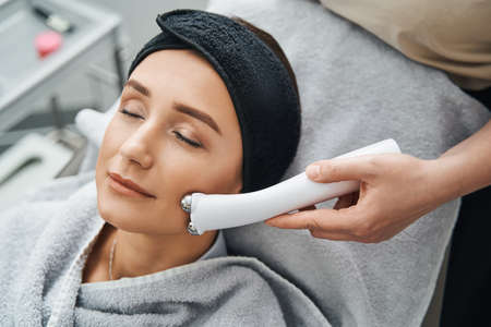 Young patient getting a microcurrent facial in a dermatologist officeの写真素材