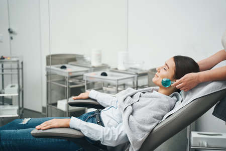 Cosmetologist massaging the patient face with an ice globeの写真素材