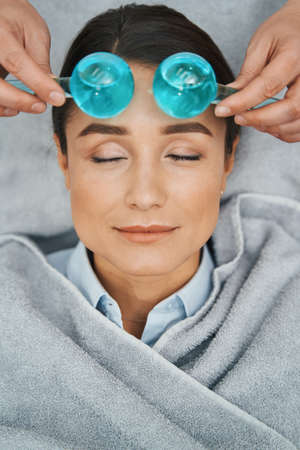 Serene woman patient having her forehead massaged with ice globesの写真素材