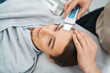 Female patient daydreaming during the facial skin cleansing procedureの写真素材