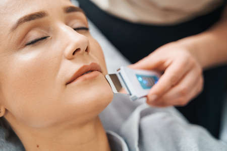 Patient having her pores unclogged with an ultrasonic skin scrubber