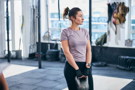 Calm female holding a kettlebell with both handsの写真素材