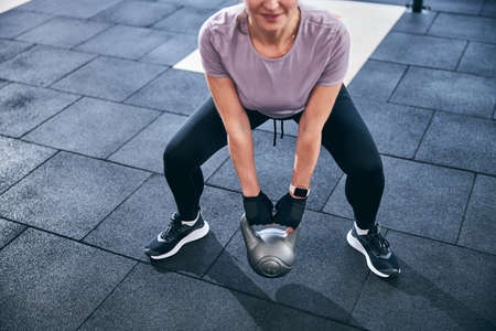 Smiling athletic female performing the two-handed kettlebell deadliftの写真素材