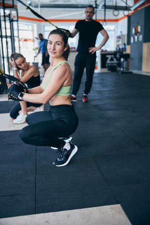 Calm sportswoman posing at the gym among her fitness partners