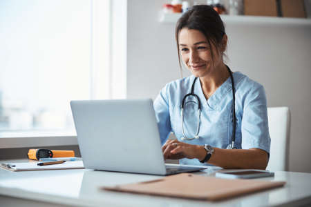 Joyful female doctor using notebook in clinicの写真素材