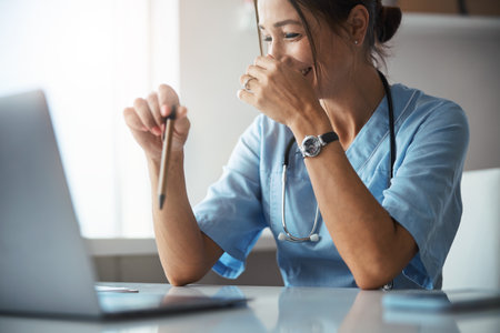 Cheerful female doctor using modern laptop in clinicの写真素材