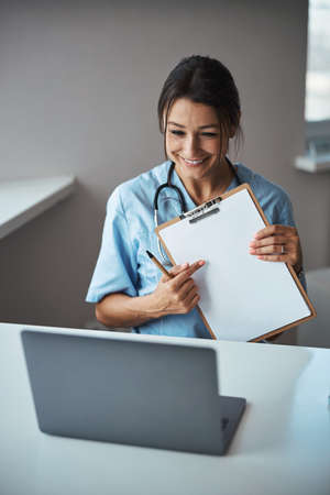 Joyful female doctor giving online consultation in clinicの写真素材