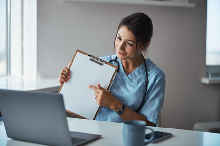 Charming female doctor giving online consultation in clinic