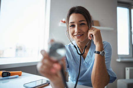 Cheerful female doctor using stethoscope in clinicの写真素材