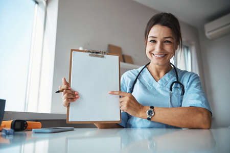 Cheerful female doctor holding clipboard and smiling
