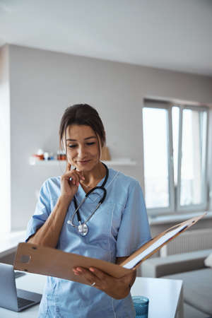 Charming female doctor studying documents in clinic