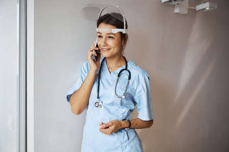 Smiling female doctor talking on cellphone in clinicの写真素材