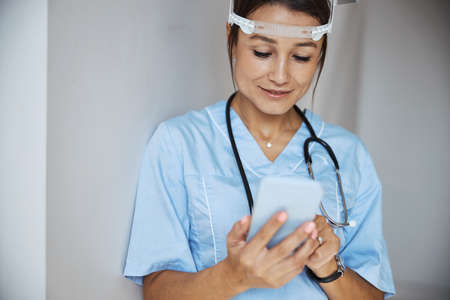 Charming female doctor using mobile phone in clinicの写真素材