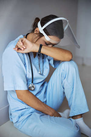 Tired female doctor sitting on the floor in clinicの写真素材