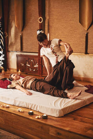 Specialist of Thai massage lifting leg of clientの写真素材