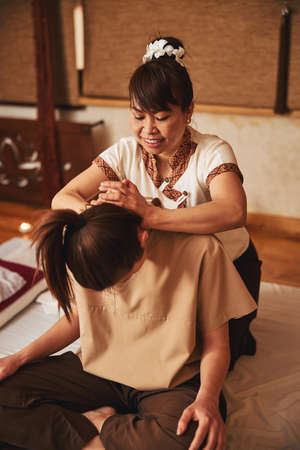 Masseuse locking her hands and pressing on female neckの写真素材