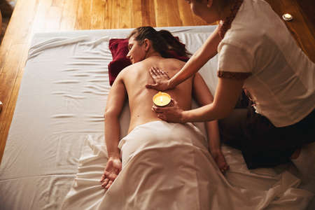 Back massage treatment with wax candle of resting ladyの写真素材