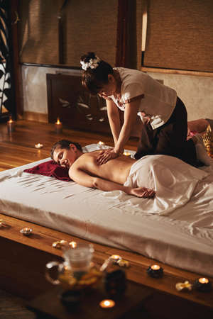 Thai massage salon specialist stroking woman back with handsの写真素材