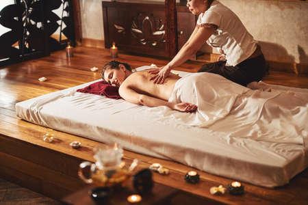 Masseuse doing hand strokes on lady back during Thai massageの写真素材