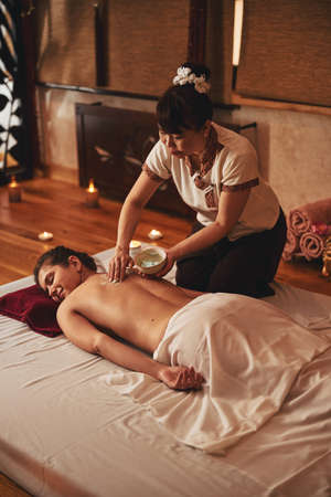 Thai woman smearing massage cream on lady backの写真素材