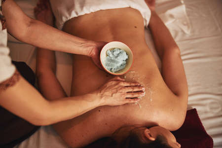 Smearing of organic cream for massage on client back