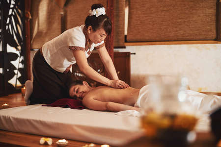 Trained massagist applying stones to skin of enjoying womanの写真素材