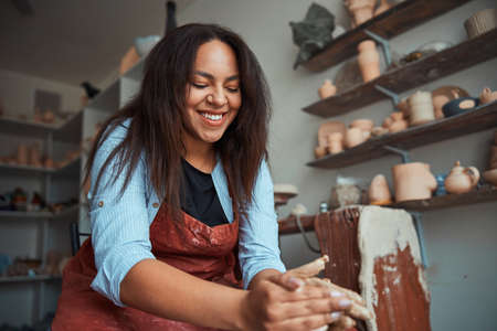 Cheerful woman ceramist making pottery in workshopの写真素材