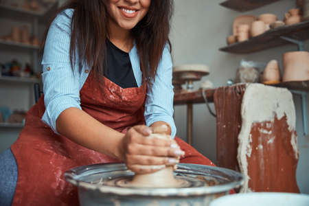 Joyful young woman making pottery in workshop