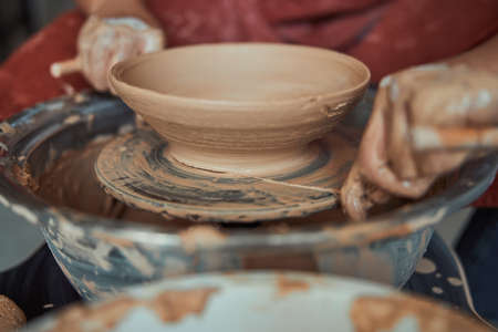 Female potter hands making clay bowl in pottery workshop