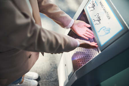 Female person using automatic hand sanitizer at airportの写真素材