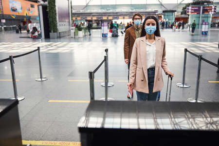 Passengers in medical masks standing in line at airportの写真素材