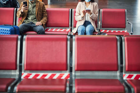 Passengers using cellphones while waiting for the flight at airportの写真素材