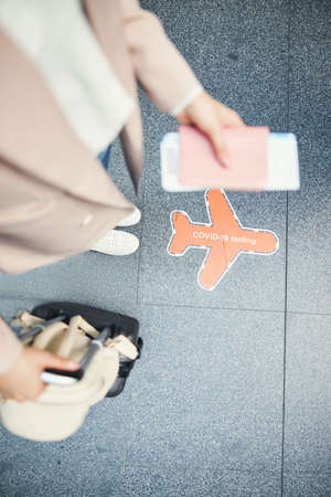 Young woman standing near covid-19 testing sign at airport